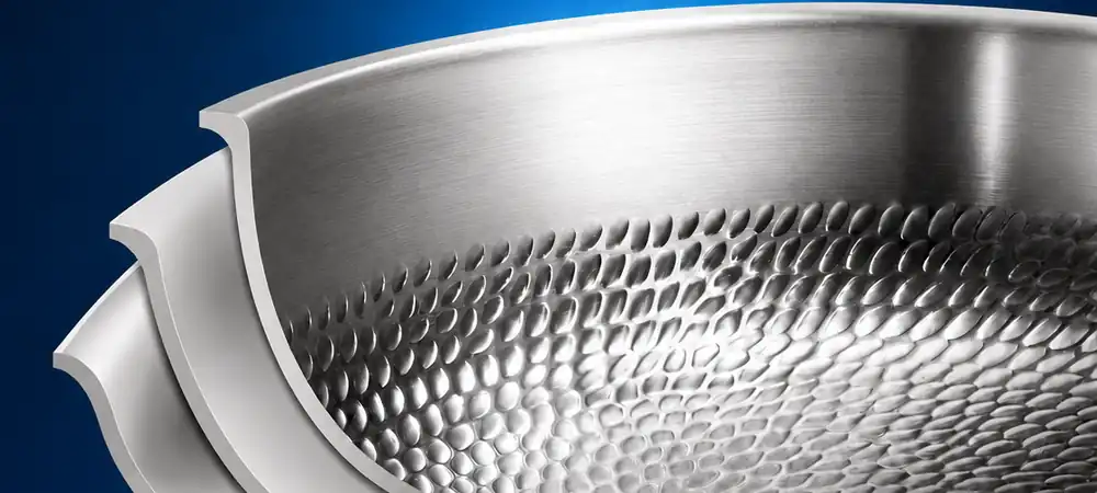Cross-section of multilayer titanium cookware with a smooth outer surface and hammered titanium cooking interior.
